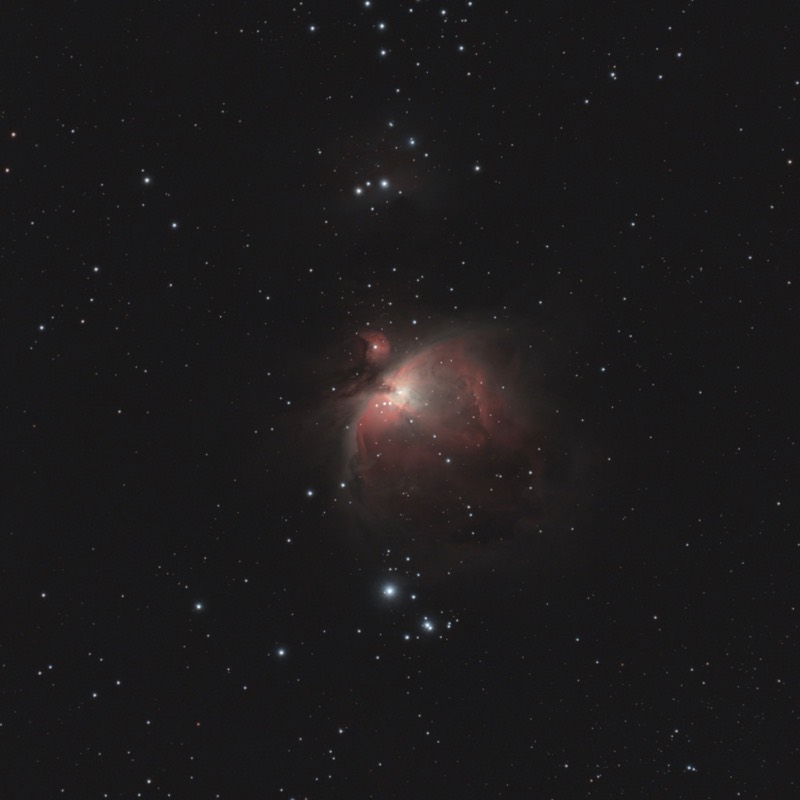 The Orion Nebula: a cloud of red and grey dust around a bright core, with the Running Man nebula above it and a field of stars behind.